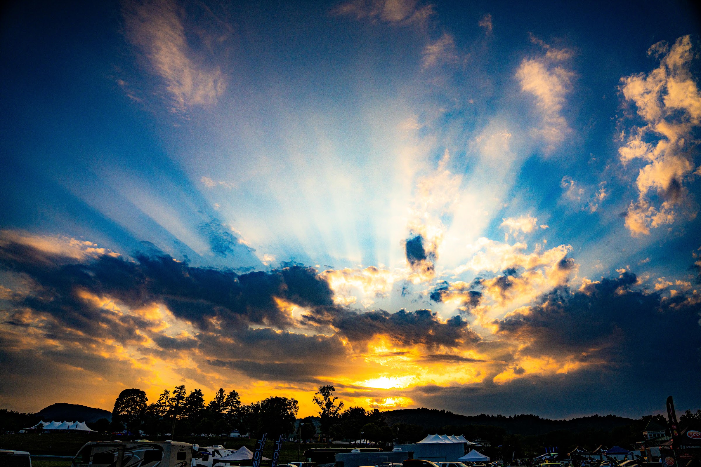 Sunburst through dramatic clouds over the trackside treeline