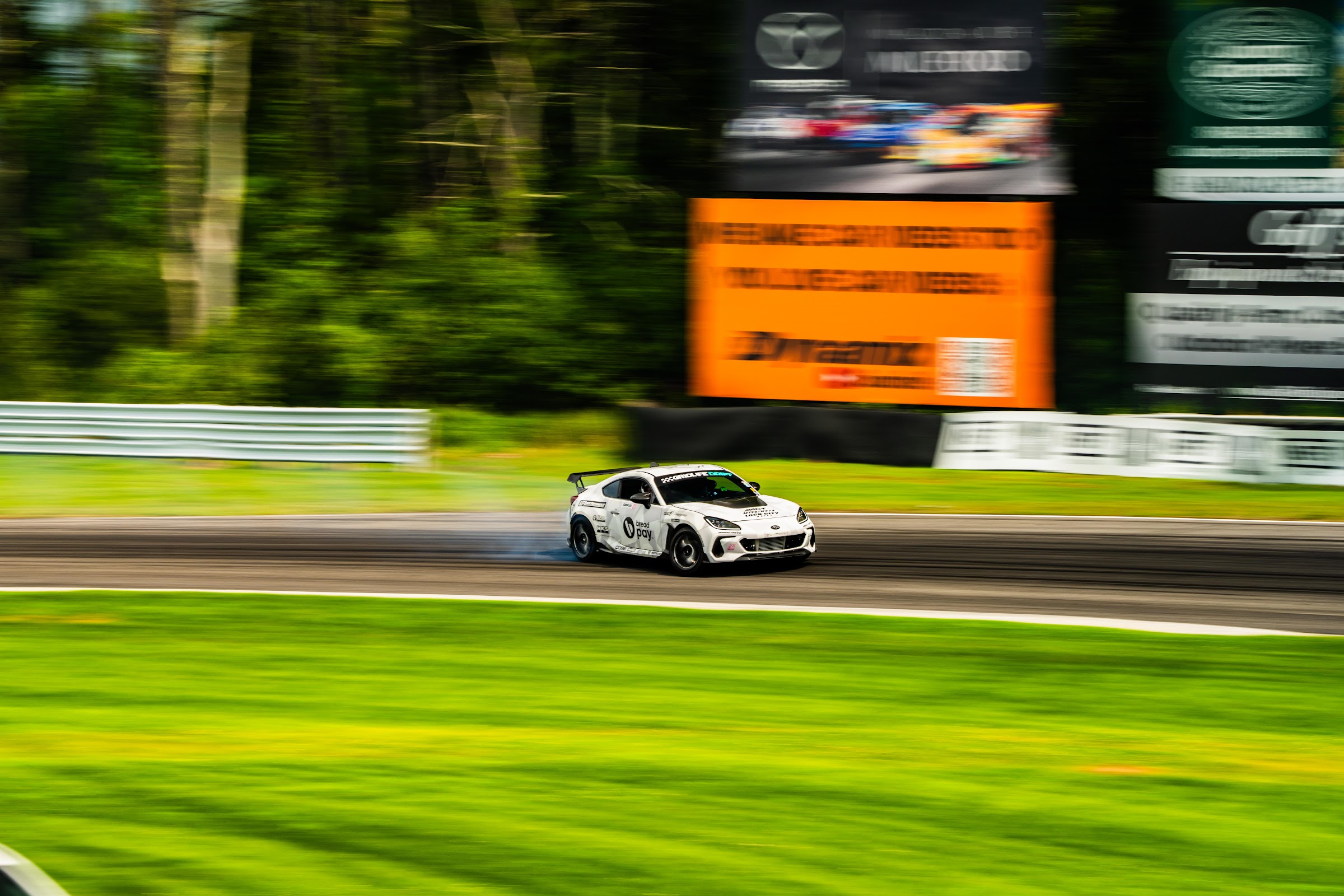 Race car panned at speed past trackside signage