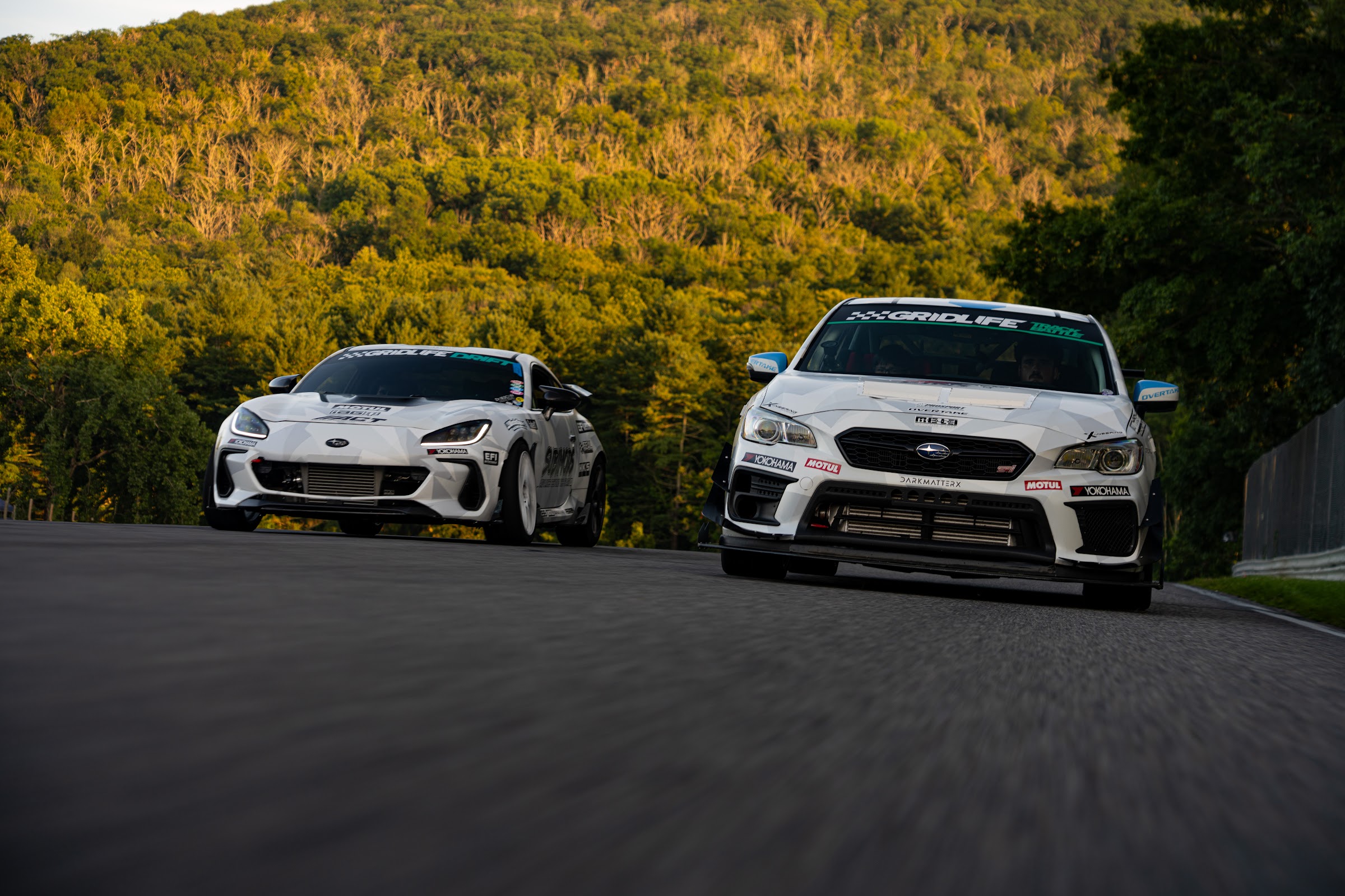 Two Subarus nose to tail cresting the hill