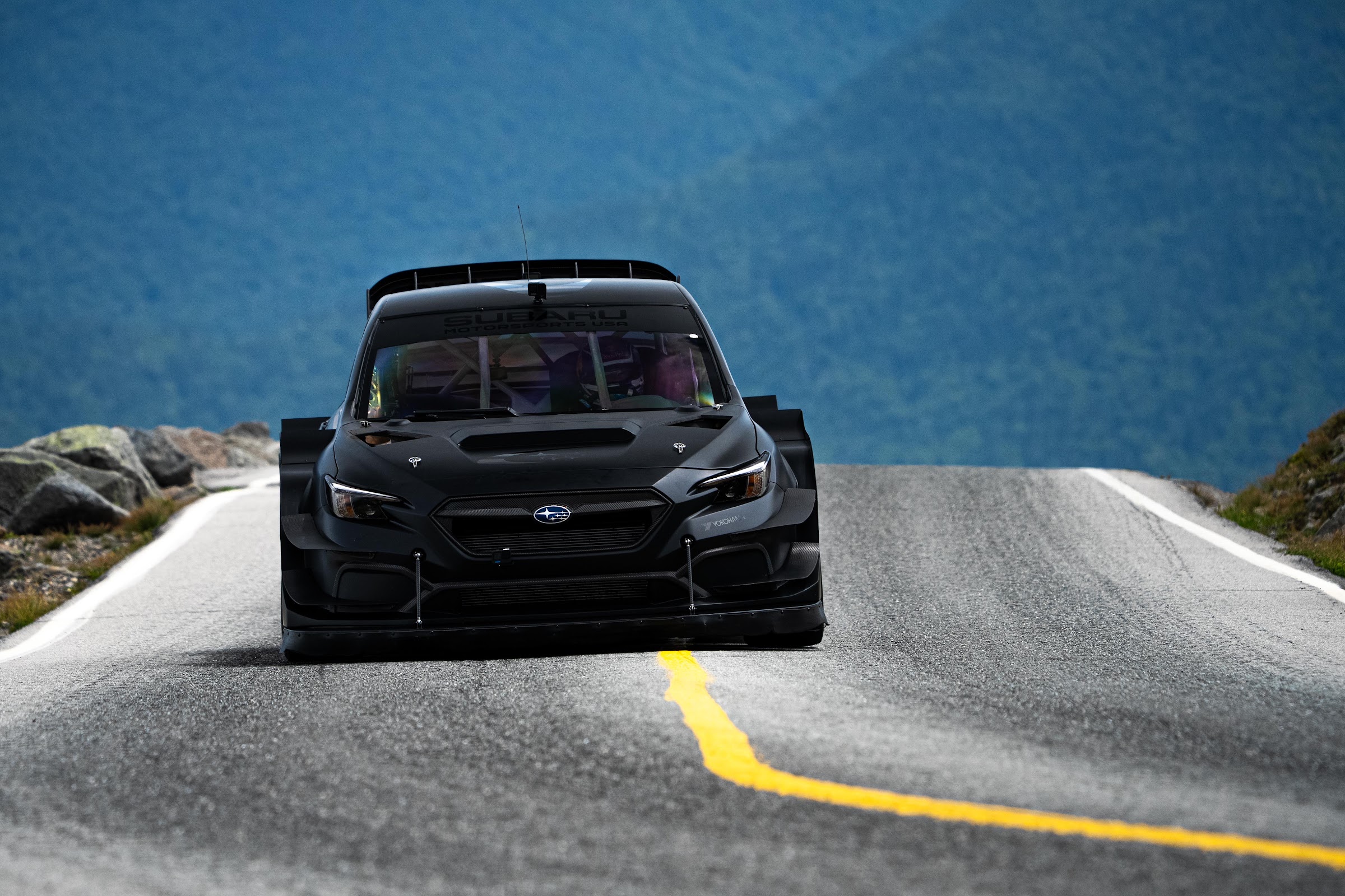 Blacked-out rally-spec Subaru head-on at the apex