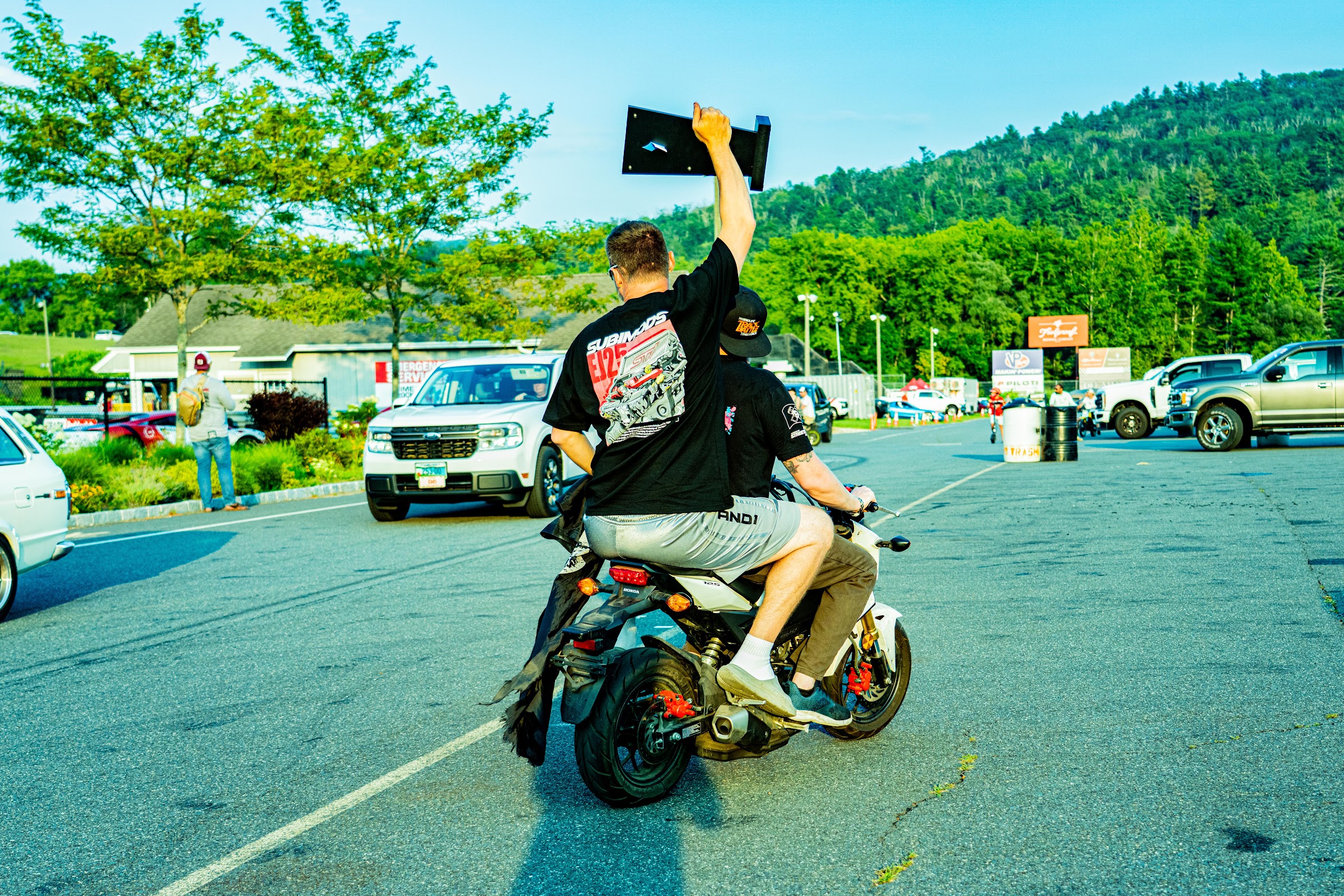 Rider popping a wheelie down the paddock road with a flag
