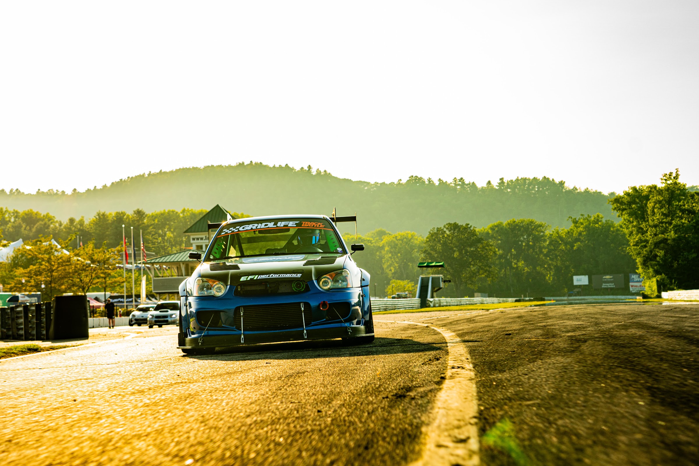 Blue STI rolling shot with golden hillside behind