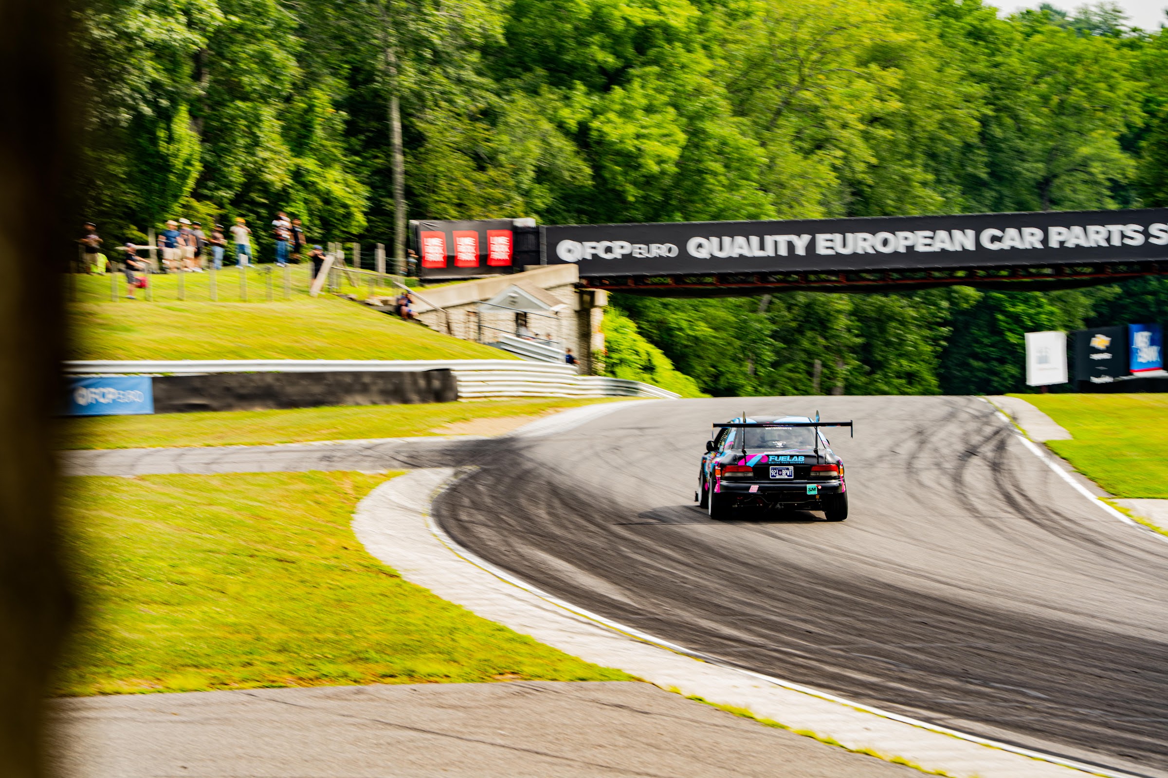 Race car cresting the uphill esses at Lime Rock Park