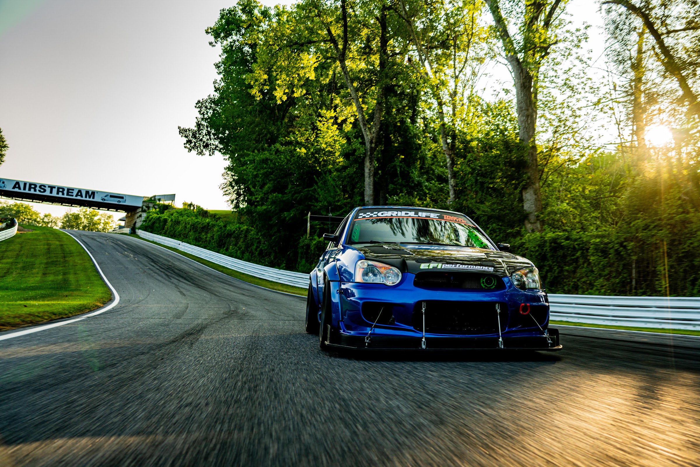 Blue STI rolling shot into golden-hour light