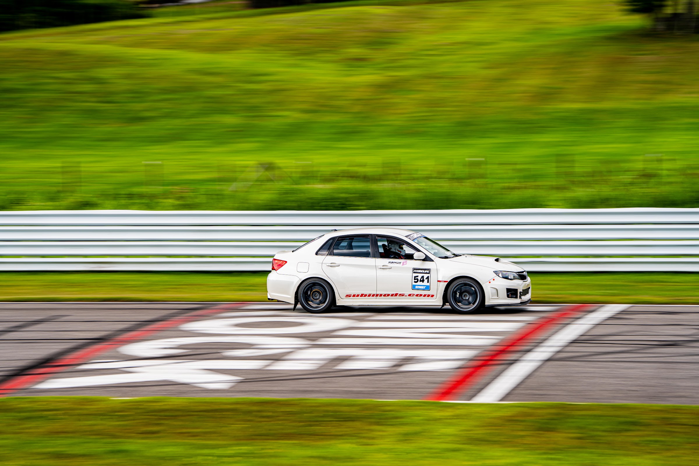 White WRX time-attack car on the front straight curbing
