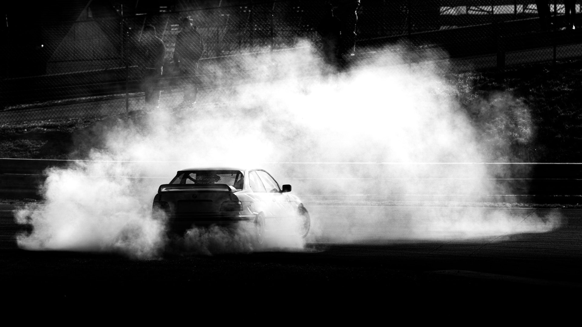 Car drifting on a track enveloped in tire smoke