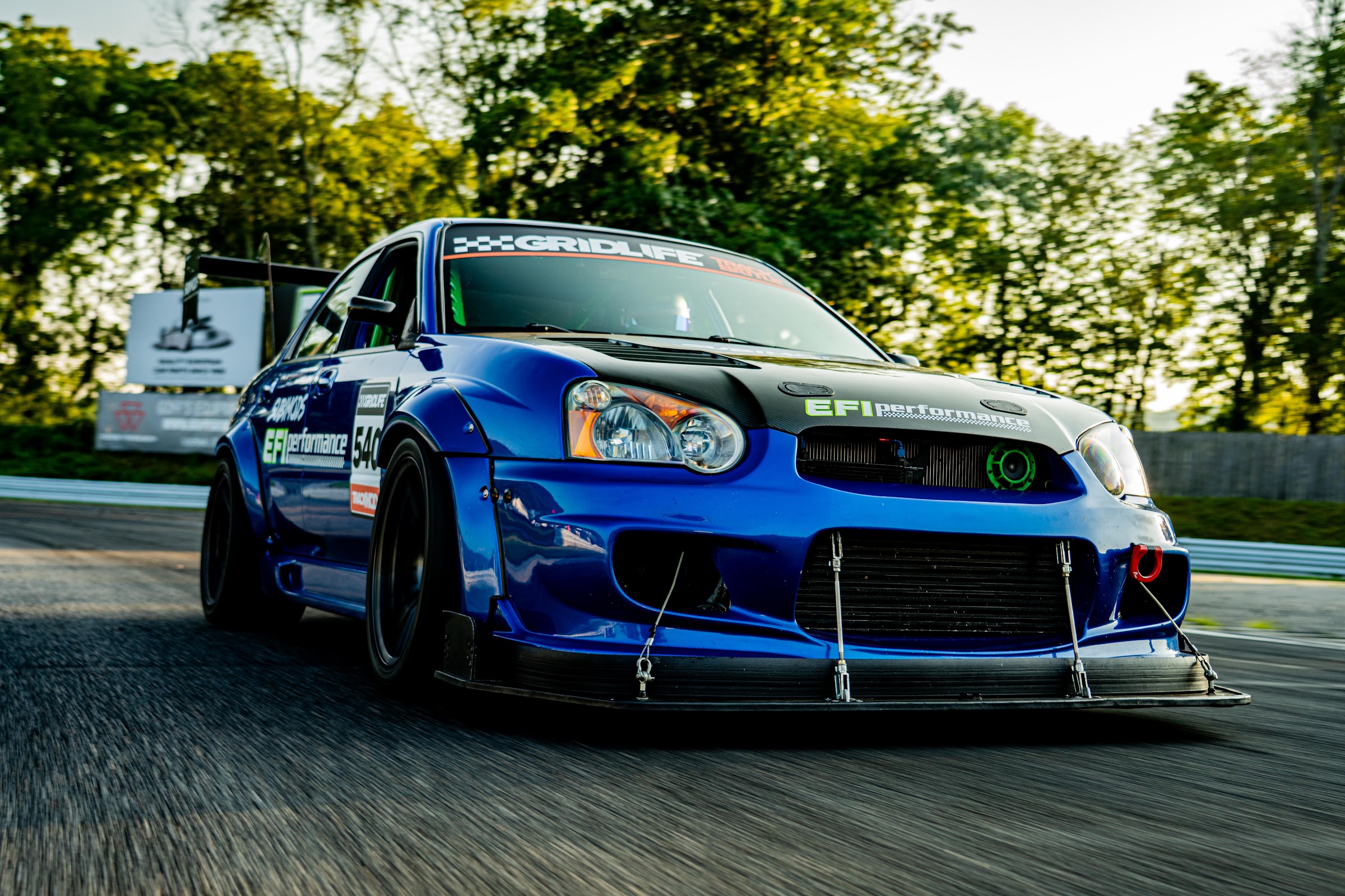 Low front three-quarter rolling shot of the blue STI