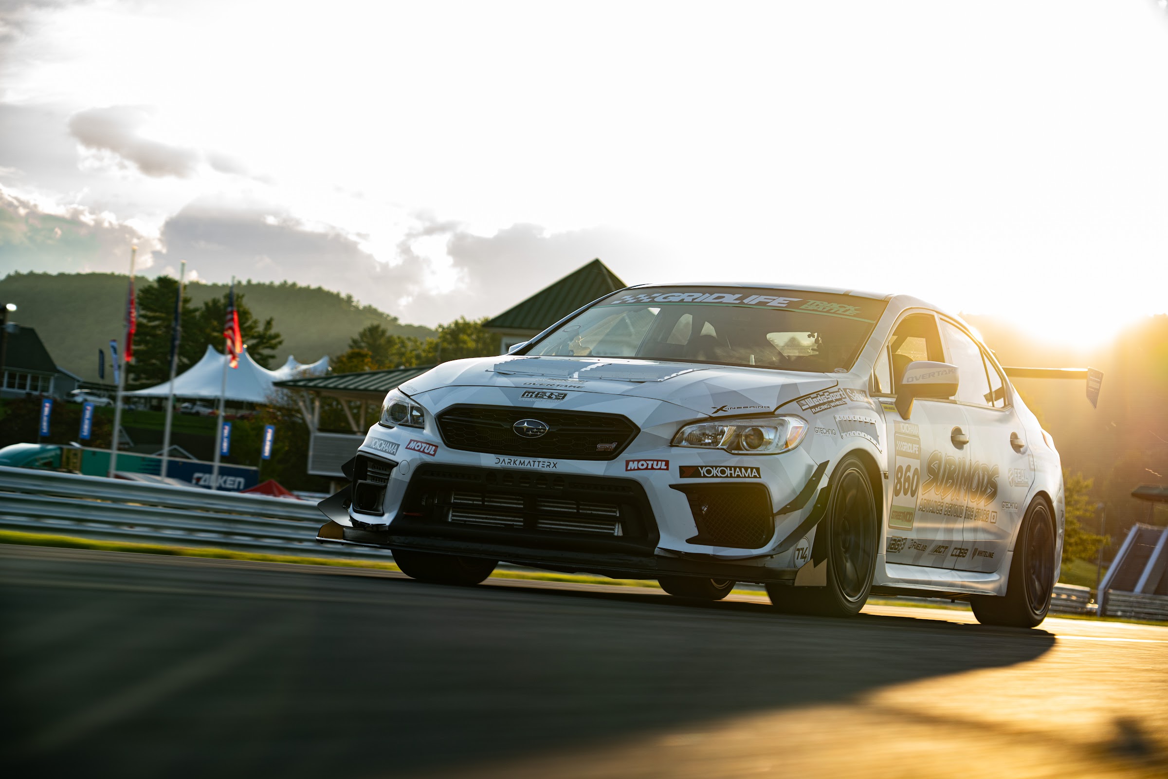 White STI backlit by low sun on track