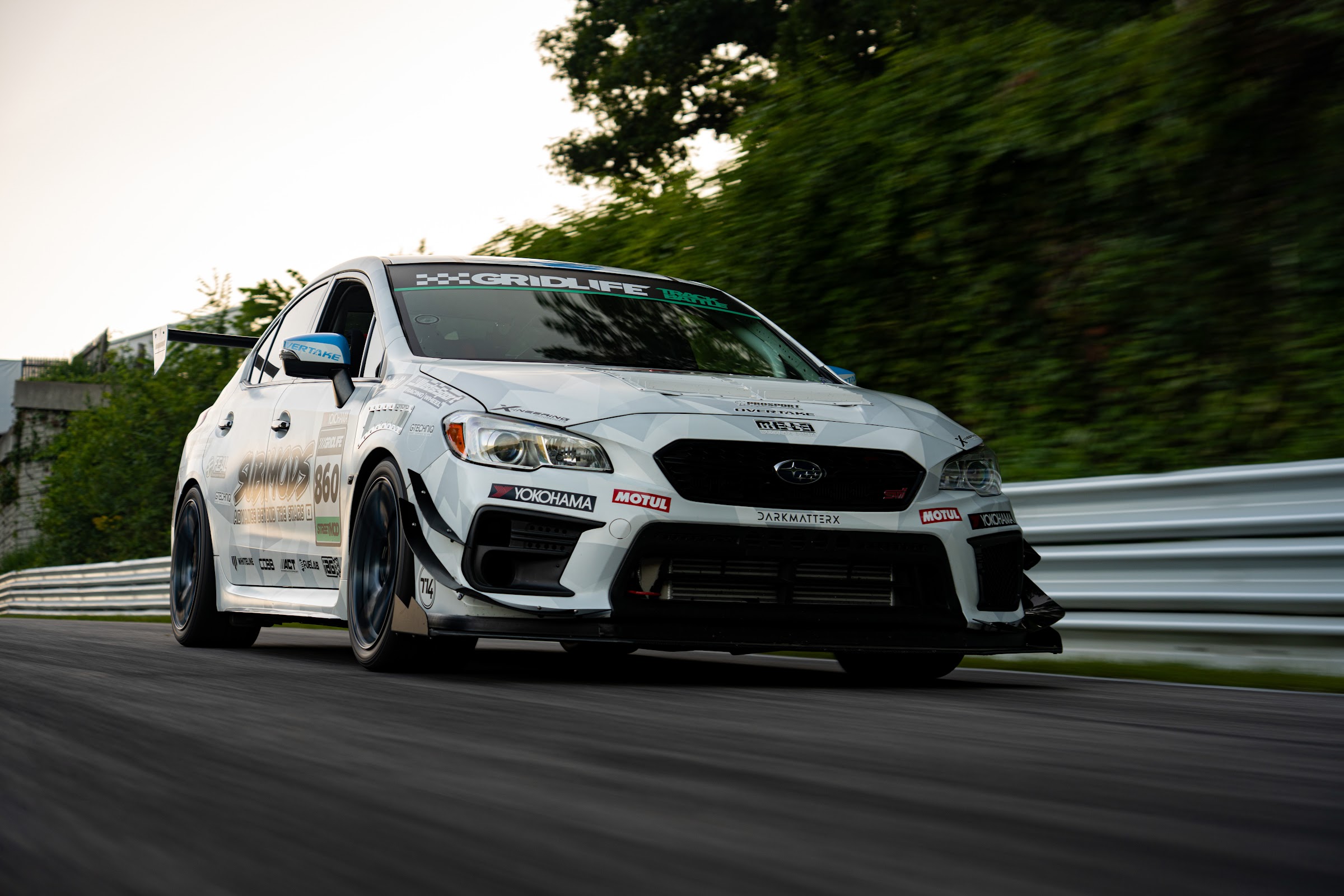 White WRX at full lean through a fast sweeper